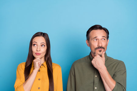 Portrait of minded charming lady handsome man arm touch chin look empty space isolated on blue color backgroundの写真素材