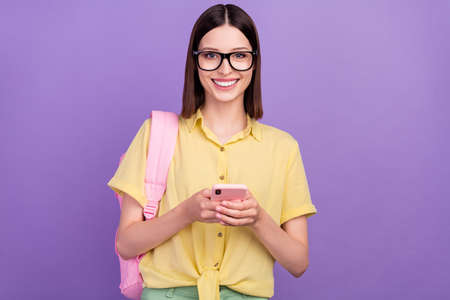 Photo of young cheerful girl use mobile repost comment blogging learn academic isolated over violet...