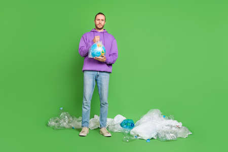 Full length photo of warn guy hold earth plastic bag litter lie floor recycle activist volunteer concept isolated over green color backgroundの写真素材