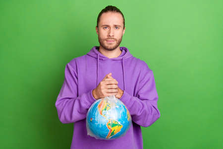 Photo of serious activist volunteer man hold earth plastic bag ask protect planet wear sweater isolated over green color backgroundの写真素材