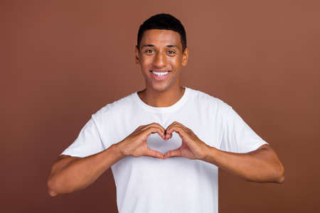 Photo of young cheerful afro guy show fingers heart symbol dream feelings isolated over brown color backgroundの写真素材