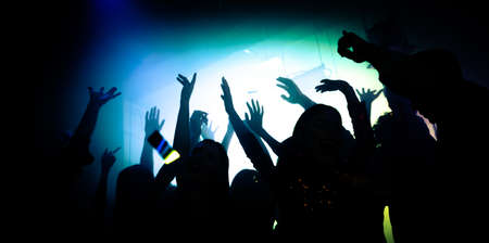 Photo of crazy bachelors enjoy dj rock star performance in private bar raise hands up dance shadow neon lightsの写真素材