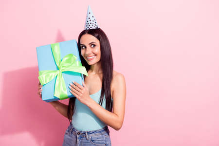 Photo portrait pretty brunette keeping big present box looking copyspace in headwear isolated pastel pink color backgroundの写真素材