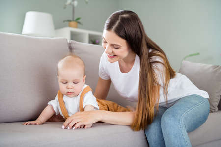 Photo of sweet adorable mother dressed white t-shirt sitting couch playing child smiling inside...