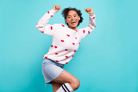 Photo of impressed excited afro girl wear heart print pullover smiling rising fists isolated blue...