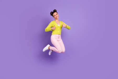 Full size photo of young happy smiling positive girl jumping showing thumb-up isolated on purple...