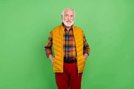 Photo of dreamy sweet mature man dressed yellow waistcoat smiling looking empty space isolated green color backgroundの写真素材