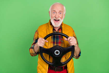 Photo of charming impressed mature man dressed yellow waistcoat smiling riding auto isolated green...