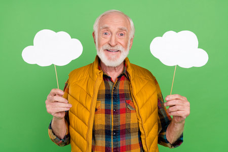 Photo of charming cute mature man dressed yellow waistcoat holding two speaking bubbles empty space...