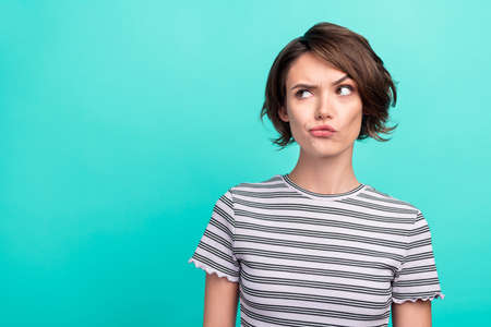 Photo of young attractive girl serious brainstorming think minded look empty space isolated over teal color backgroundの写真素材