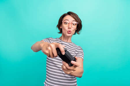 Photo of young excited girl pouted lips play video game joystick console isolated over turquoise color backgroundの写真素材