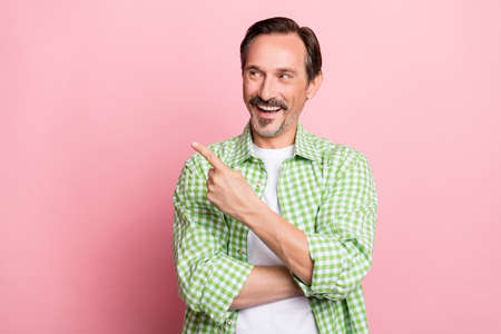 Photo of handsome excited young guy dressed green plaid shirt smiling pointing looking empty space...