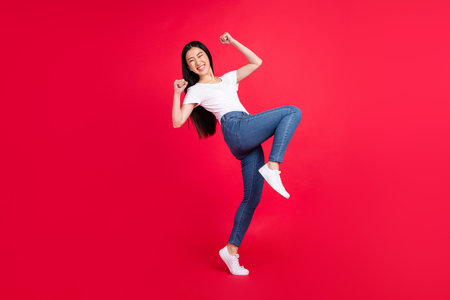 Full body profile side photo of young attractive asian girl happy positive smile rejoice victory isolated over red color backgroundの写真素材