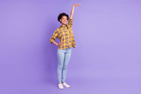 Full size photo of young african girl happy positive smile show hand length big size isolated over purple color backgroundの写真素材
