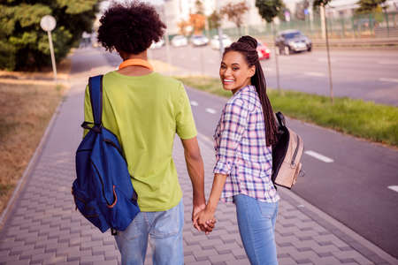 Rear back behind view portrait of attractive cheerful couple spending romantic date day strolling going holding hands outdoorsの写真素材
