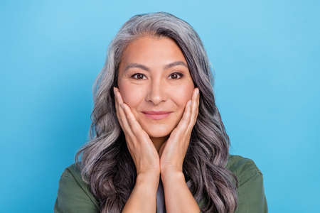 Photo of nice aged grey hairdo lady hands face wear khaki shirt isolated on blue color background