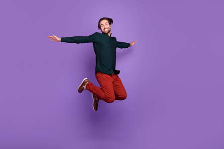 Photo of carefree funny young man wear smart casual outfit smiling jumping high arms sides isolated purple color backgroundの写真素材