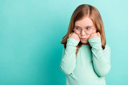 Photo of young girl unhappy upset negative hands touch cheeks offended depressed isolated over teal color backgroundの写真素材