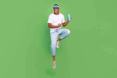 Full body photo of young afro guy indicate finger paper cup ads choice select isolated over green...