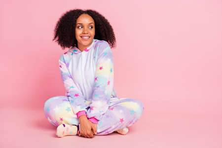 Full size photo of young cheerful african girl sit lotus pose look empty space kigurumi isolated over pink color backgroundの写真素材
