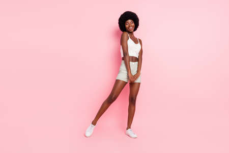 Photo of charming funny shy lady laugh posing wear cropped top shorts sneakers isolated pink color backgroundの写真素材