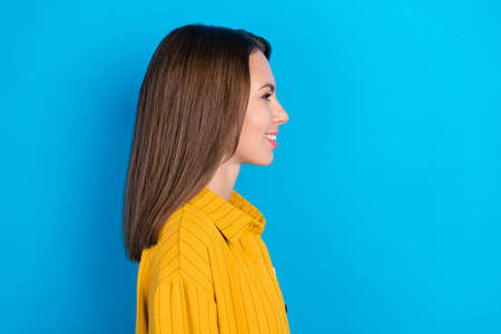 Profile side photo of cheerful young lady good mood look empty space isolated over blue color backgroundの写真素材