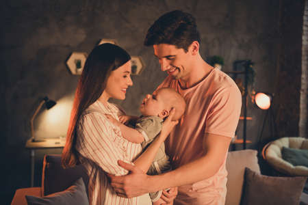 Portrait of attractive idyllic cheerful family parenthood cuddling toddler late night at home house...