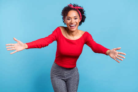 Photo of friendly excited african lady dressed red off-shoulders shirt smiling ready hug you open arms isolated blue color backgroundの写真素材