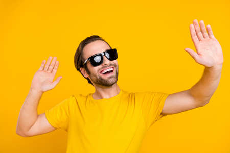 Photo of young cheerful guy have fun dancing enjoy vacation eyewear isolated over yellow color backgroundの写真素材