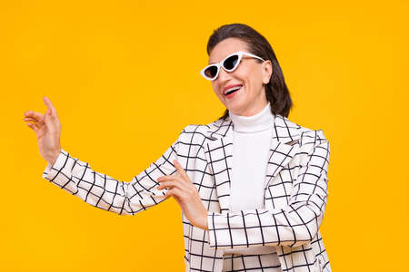 Photo of excited positive aged lady have fun dancing partying isolated on yellow color backgroundの写真素材