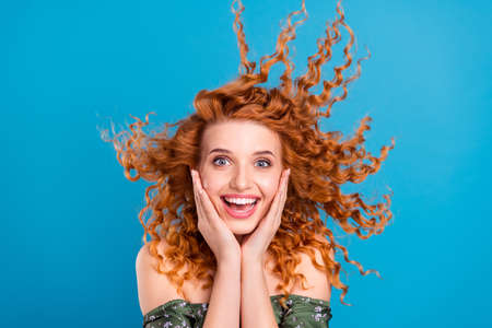 Photo of young girl happy positive smile hands touch cheeks amazed sale news isolated over blue color backgroundの写真素材