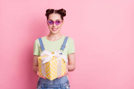 Photo portrait girl in overall sunglass keeping present box looking copyspace isolated pastel pink color backgroundの写真素材