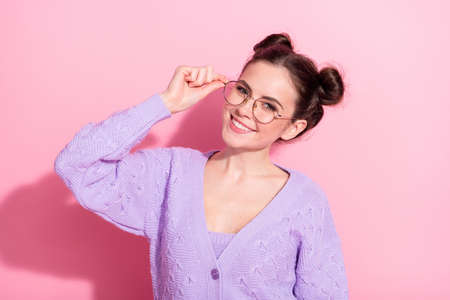 Photo portrait of cheerful cute woman with top knot hairstyle smiling isolated on pastel pink color backgroundの写真素材