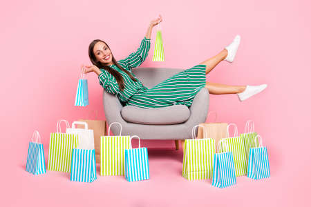 Full size profile side photo of young cheerful girl sit lounger enjoy shopping boutigue wardrobe isolated over pastel color backgroundの写真素材