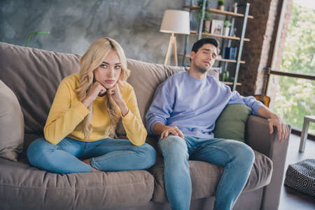 Photo of young couple unhappy sad negative disagreement conflict moody bad problem bored sit couch indoorsの写真素材