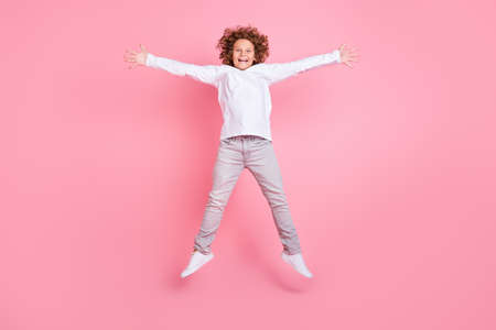 Full length photo of excited happy cheerful child jump up raise hands star shape isolated on pink color backgroundの写真素材