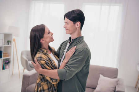 Photo of beautiful adorable young lovers dressed casual clothes hugging looking eyes smiling indoors...
