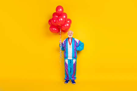 Full length photo of senior man workout hold many ball inflate helium open new sportive mall isolated over yellow color backgroundの写真素材