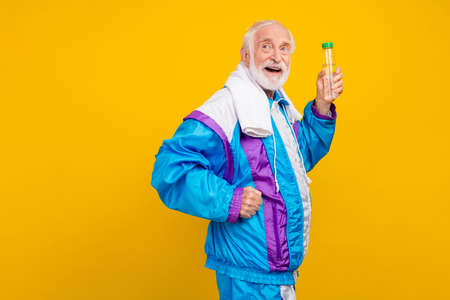 Profile side photo of senior man workout drink water effort towel regime sweating isolated over yellow color backgroundの写真素材