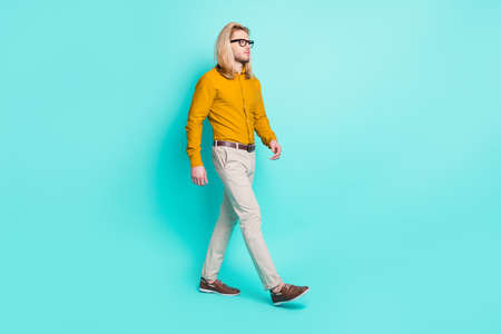 Full size profile side photo of young man happy positive smile go walk step look empty space isolated over turquoise color backgroundの写真素材
