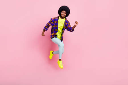 Full length body size view of attractive cheerful active girl jumping running motivation isolated over pink pastel color backgroundの写真素材