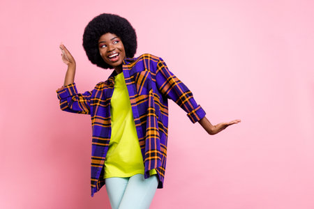 Portrait of attractive cheerful girl wearing checked shirt dancing having fun isolated over pink pastel color backgroundの写真素材