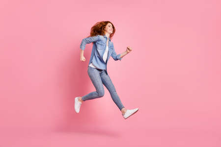 Full body photo of charming nice happy young woman look run jump empty space isolated on pink color backgroundの写真素材