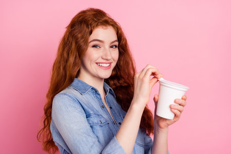 Photo of happy cheerful sweet young woman open cup of dairy smile isolated on pastel pink color backgroundの写真素材
