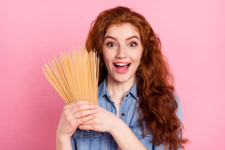 Photo of shiny excited young lady dressed jeans shirt smiling holding pasta isolated pink color backgroundの写真素材