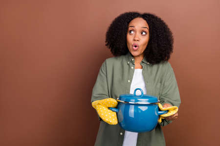 Photo of impressed brunette millennial lady cook meal look promo wear khaki shirt isolated on brown color backgroundの写真素材