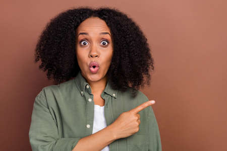 Photo of hooray brunette millennial afro hairstyle lady indicate empty space wear military shirt isolated on brown color backgroundの写真素材