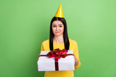 Portrait of attractive skeptic girl holding giftbox dislike unpleasant isolated over green color...