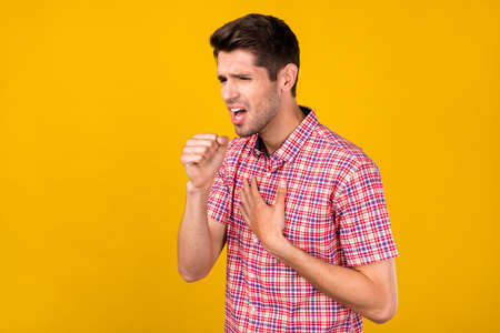 Profile side photo of young guy hands touch chest symptom coughing coronavirus isolated over yellow color backgroundの写真素材