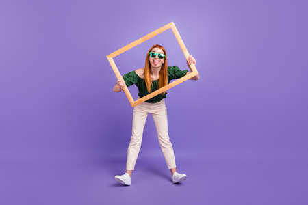 Full size photo of funny red hair young lady with frame wear spectacles blouse trousers isolated on violet backgroundの写真素材